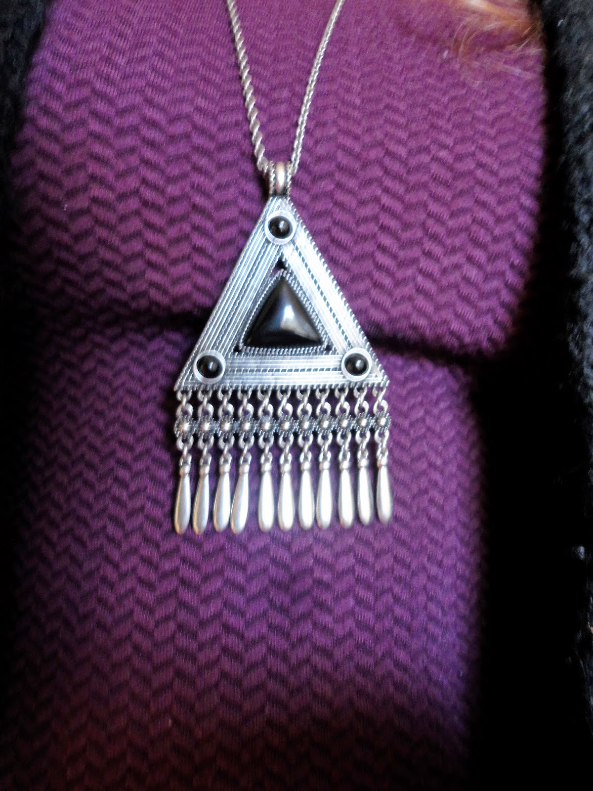 black and silver triangular pendant on purple dress