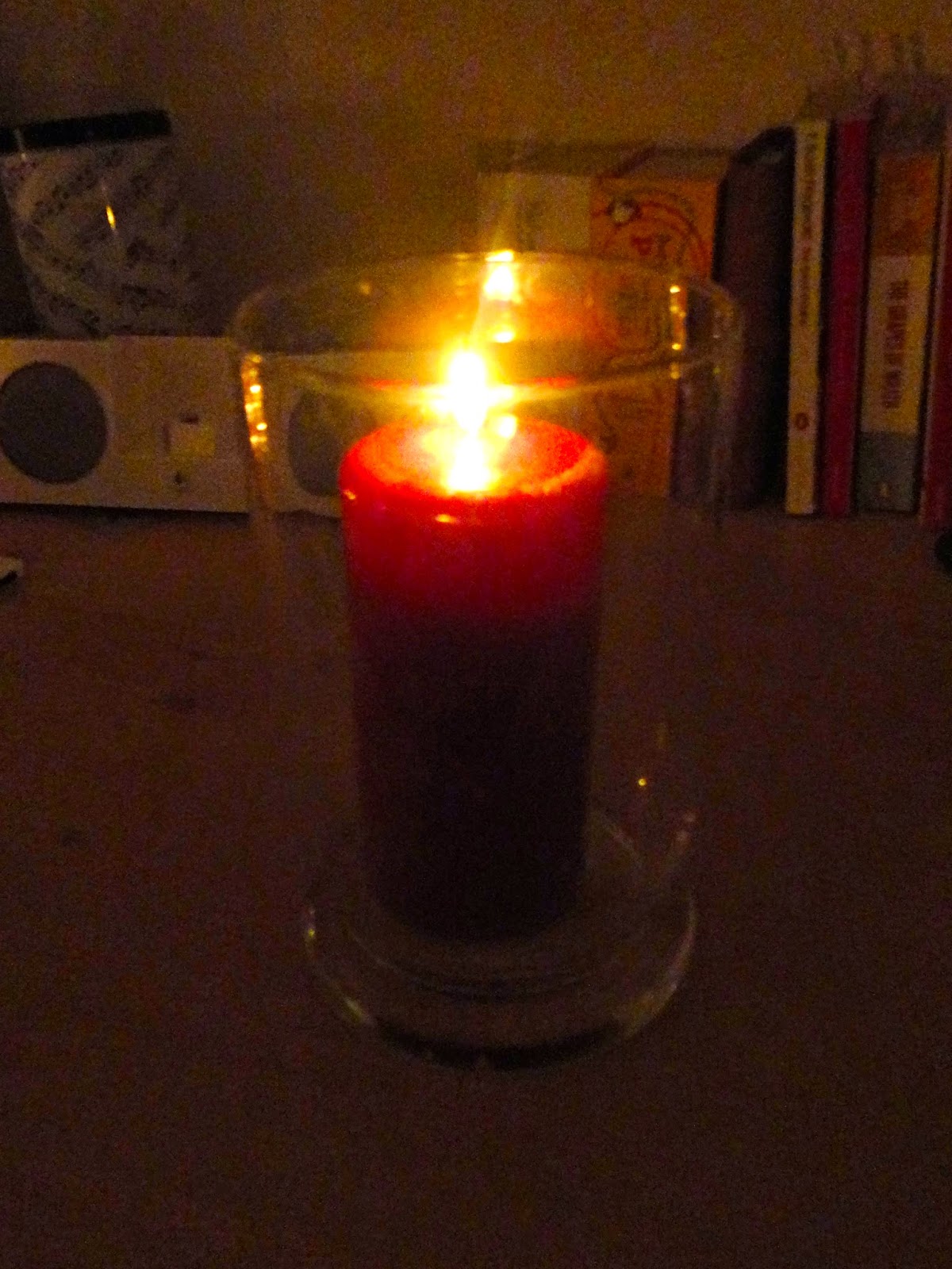 Red scented pillar candle lit in glass hurricane jar