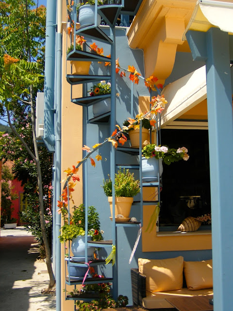 Spiral stair with flowerpots on colourful building | Architecture in the town of Fiskardo, Kefalonia, Greece