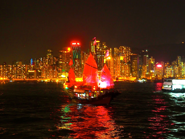 A Symphony of Lights | view of Hong Kong island and Victoria Harbour from TST promenade at night, with traditional Chinese junk boat