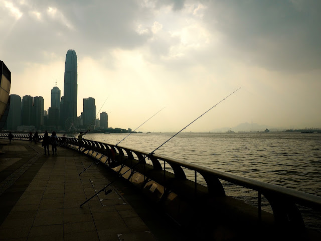 Fishing poles at sunset / dusk beside Victoria Harbour, taken from Wan Chai / Exhibition Centre Pier, and overlooking Central skyscrapers of Hong Kong