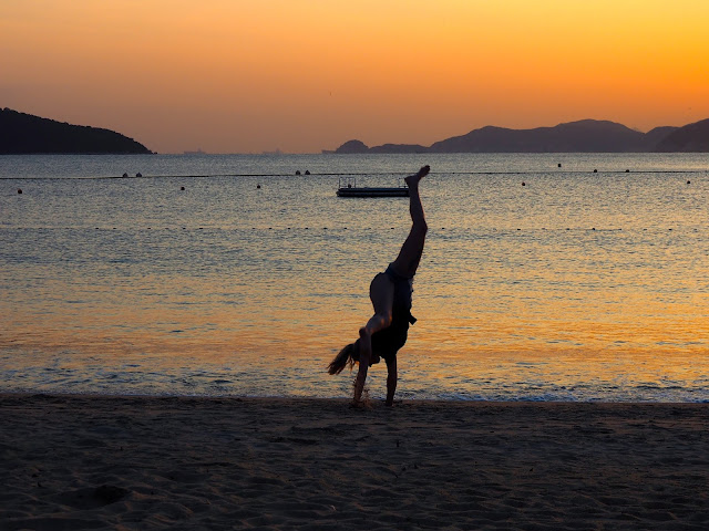 Silhouette of a girl doing a cartwheel in the sand at sunset on Repulse Bay Beach, Hong Kong