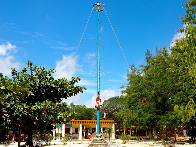 Men swinging upside down around a pole, in a prayer ceremony, outside Tulum ruins, Mexico