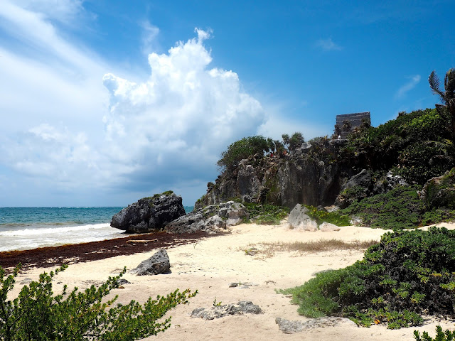 White sandy beach with Tulum ruins on the cliff in the background, Mexico