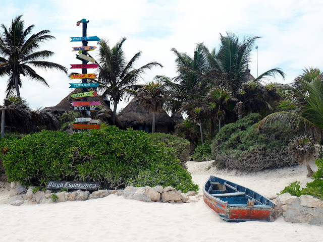 Old fishing boat and colourful direction sign on Tulum beach, Mexico