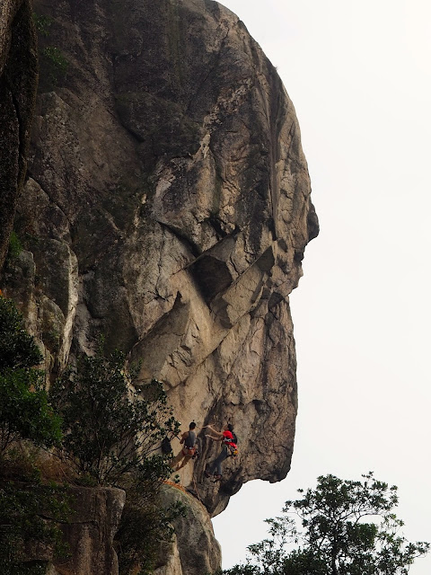 Lion's head rock formation of Lion Rock, with rock climbers on the face, in New Territories, Hong Kong