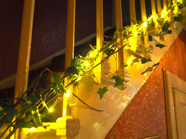 Stair case in the hallway decorated for Christmas with twinkly lights and green leaf foliage