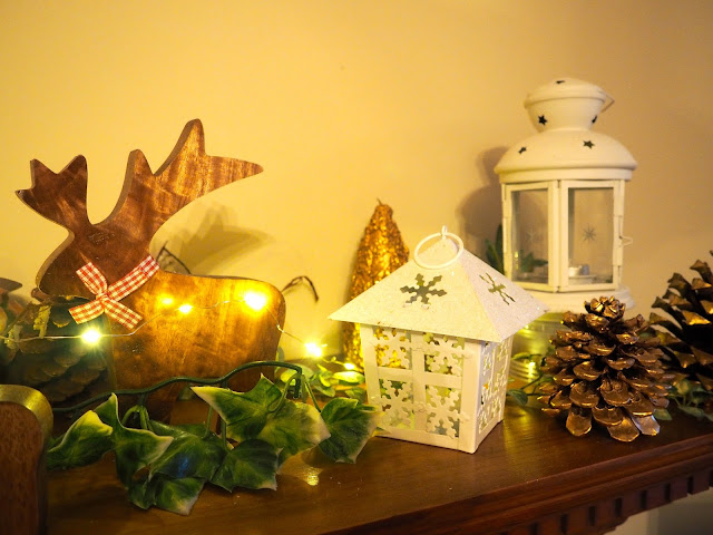 Christmas decorations in the living room, with wooden reindeer, snowflake lanterns, pine cones, leaves and lights