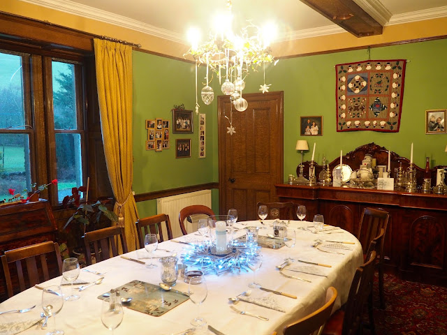 The dining room for Christmas dinner, with silver bauble, fairy lights, candles, and natural leaf and stick wreaths