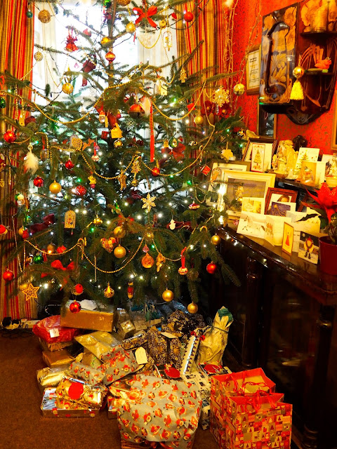 Christmas tree with presents underneath and cards on the sideboard