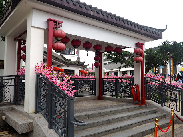 Chinese style pagoda / pavilion with red lanterns and pink blossom in Ngong Ping village, Lantau Island, Hong Kong