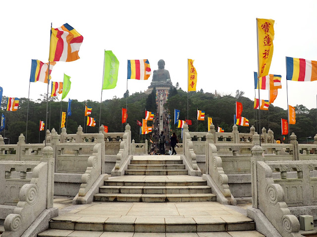 View of the Big Buddha / Tian Tan Buddha with colourful flags across the podium in Ngong Ping Piazza, Lantau Island, Hong Kong