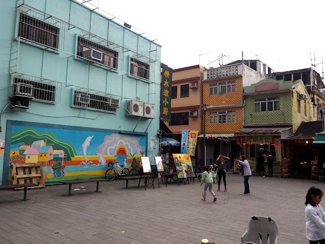 Town square with colourful mural and children playing in Tai O fishing village, Lantau Island, Hong Kong