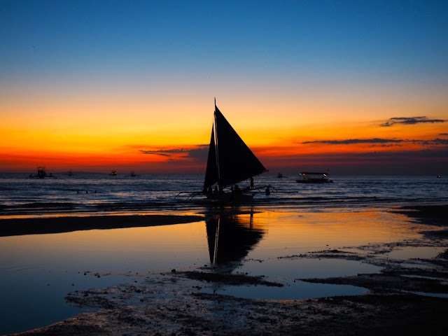 Sail boat silhouette with reflection at sunset on White Beach, Boracay, Philippines
