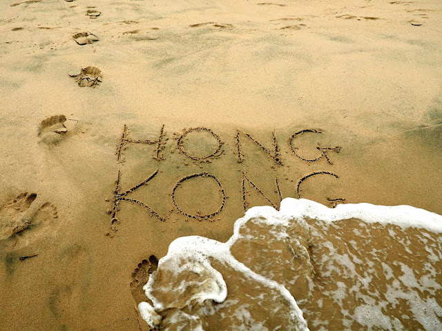 "Hong Kong" written in the sand, with wave starting to wash it away