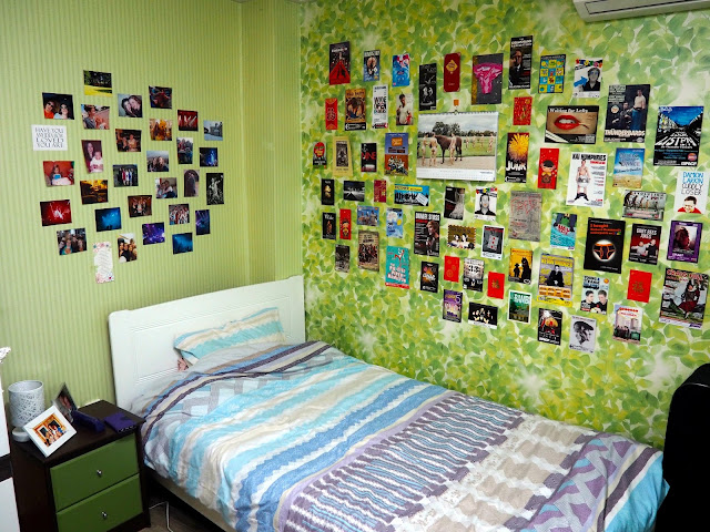 Bed area, with bedside table and pictures and photos decorating the walls, inside studio apartment in Busan, South Korea