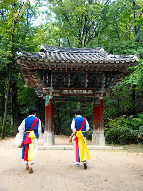 Musicians in traditional costume, walking through an arch at the Korean Folk Village, Yongin, Gyeonggi-do, South Korea
