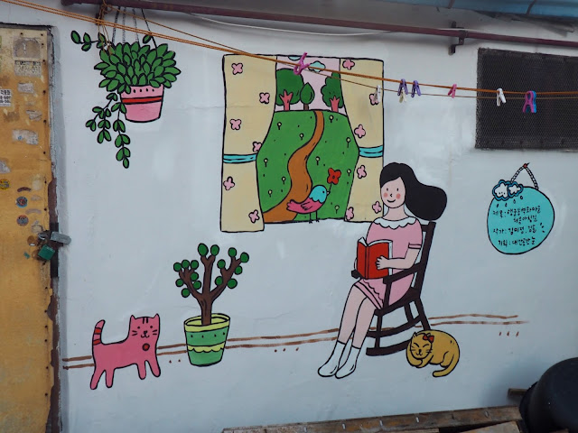 Street art of woman reading with cats in the Haenggung-dong mural village in Suwon, South Korea
