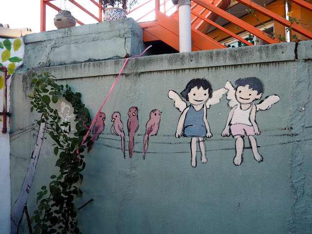 Street art of children with wings and birds on a phone line, in the Haenggung-dong mural village in Suwon, South Korea