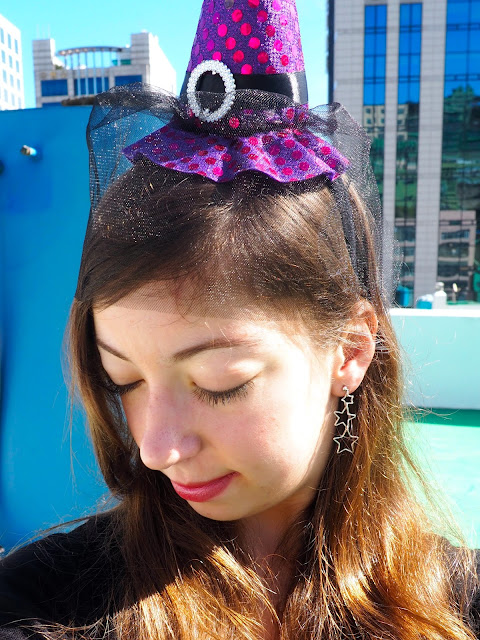 Witch Halloween Outfit | accessory details of small purple witch hat wth black veil on a headband, and silver star dangly earrings