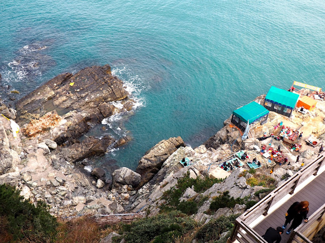 Rocks along the coast of Yeongdo Island, with seafood tents, taken from Yeongdo Lighthouse, Taejongdae Park, Busan, South Korea