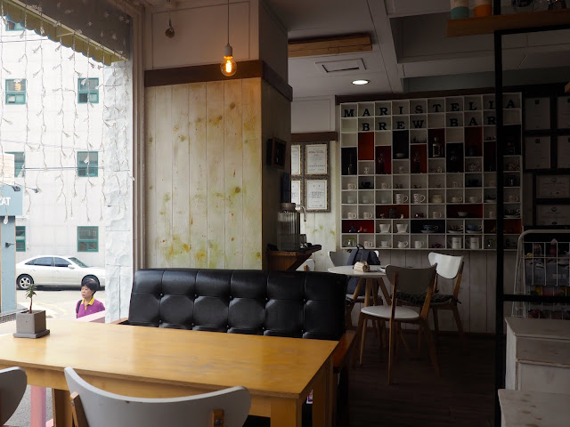 Cafe interior with tables, chairs, sofas and shelves of coffee cups in Marisstella cafe in Myeongnyun, Busan, South Korea