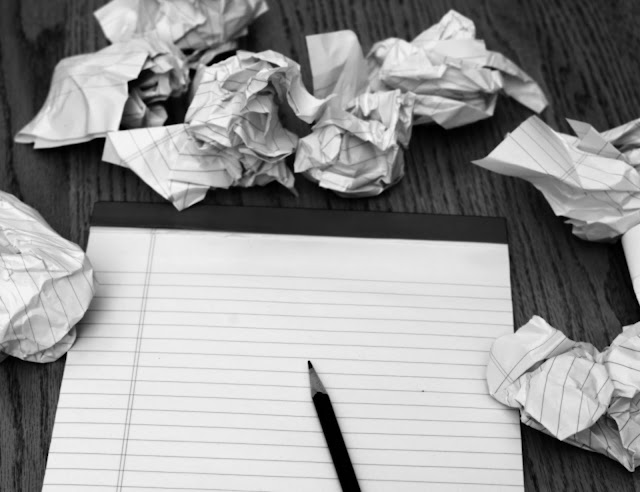 Writer's Block - blank paper with pencil and crumpled up paper scattered around