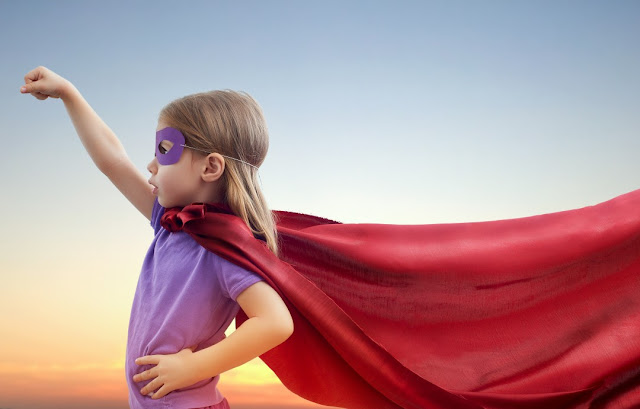 Little girl wearing superhero red cape and eye mask