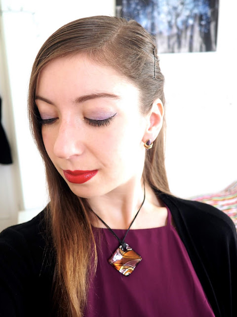 Evil Queen Disneybound villain outfit jewellery details of purple and gold stud earrings and chunky square pendant necklace, with purple eyeshadow and red lipstick