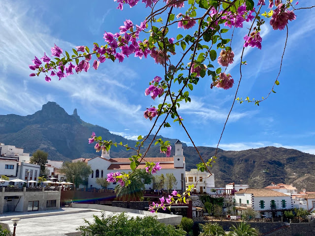 View of Tejeda church and the Roque Nublo in the mountains, with branches of flowers in the foreground - Tejeda, Gran Canaria, Spain