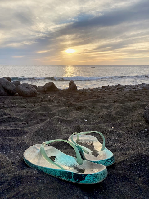 Flip flops on the black volcanic sand, sunset at the beach, near Tasartico, Gran Canaria, Spain