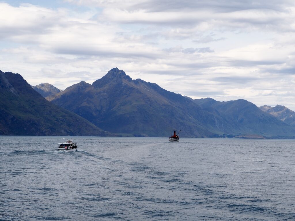 A Week in Queenstown - second feature photo - view looking across Lake Wakatipu with mountains along the far shore and two boats sailing in the foreground - New Zealand's South Island