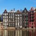 Amsterdam City Break - feature photo - tall 'dancing' houses tilting and leaning on each other along the canal waterfront near Damrak in the historic centre of Amsterdam, Netherlands